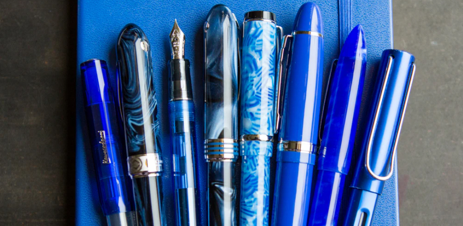 Асортимент синіх перових ручок із ковпачком і наконечником на синьому журналі